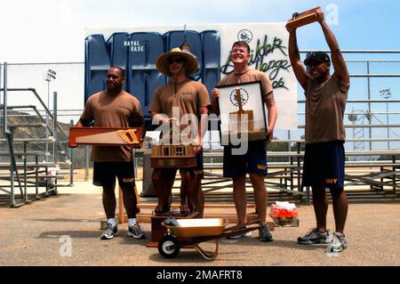 060721-N-6597H-257. [Complete] Scene Caption: 060721-N-6597H-257 (July 21, 2006)(From left-to-right), US Navy (USN) Construction Electrician 1ST Class (CE1) Yulin Wright, winner of the wood sawing competition, USN Equipment Operator 1ST Class (EO1) Aaron K. Paro, winner of the wheelbarrow race and overall event winner, USN Steel Worker 2nd Class (SW2) Will C. Bruchey, winner of the dirt shoveling competition, and USN Builder 2nd Class (BU2) Adalberto Corona, winner of the nail driving competition, celebrate after receiving their trophies during the Fourth Annual Seabee Builder's Challenge held Stock Photo