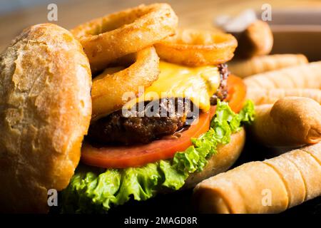 Authentic top quality American Burger with fried onion rings and cheese. Served with tequeños. Stock Photo
