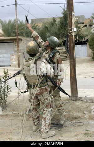 070317-M-2819S-016. [Complete] Scene Caption: An Iraqi Soldier cuts a suspicious cord during a foot patrol. Soldiers of the Iraqi Army and Marines with the Military Transition Team attached to 2nd Battalion, 2nd Brigade, and 1ST Division of the Iraqi Army conduct mounted security patrols as a combined forces exercise on March 7, 2007. Regimental Combat Team 6 is deployed with II Marine Expeditionary Force in support of Operation Iraqi Freedom in the Anbar Province of Iraq (Multi-National Forces-West) to develop the Iraqi Security Forces, facilitate the development of official rule of law throu Stock Photo