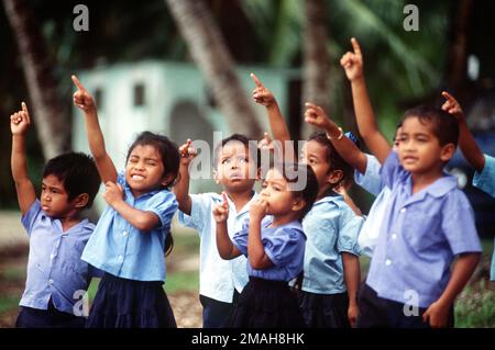 Children point to the sky as a 374th Airlift Wing aircraft passes over Peleliu during the delivery of boxes of gifts to islanders of the Federated States of Micronesia. Flown by crews from the 345th and the 21st Airlift Squadrons, the C-130 is participating in Christmas Drop '92, the 40th anniversary of the humanitarian effort. Every Christmas since 1952, food, clothing, tools and toys donated by residents of Guam have been delivered by air to 40 Micronesian islands. Country: Micronesia Stock Photo
