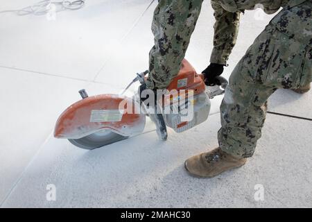 (220526-N-OI810-0299) KEY WEST, Florida (May 26, 2022) Steelworker 1st Class Leonardo Gomez, from Bogota, Colombia, assigned to Naval Mobile Construction Battalion (NMCB) 14, uses a uses a concrete saw to cut a damaged section of runway at Boca Chica Field, Naval Air Station Key West (NASKW), May 26, 2022. NMCB-14 teamed up with NASKW Public Works and NASKW Air Operations Department to complete the needed airfield damage repair. Seabees assigned to NMCB-14 travelled to NASKW to perform on-site training and assist with facility and compound maintenance. NMCB-14 provides advance base constructio Stock Photo