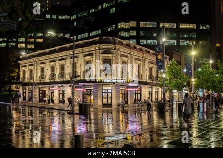 McDonalds restaurant at Circular Quay at night with colourful reflections on wet street in Sydney, Australia, on 6 January 2023 Stock Photo