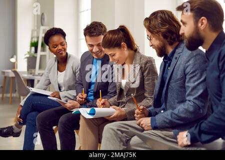 Team of happy creative people writing down ideas while working on business project together Stock Photo