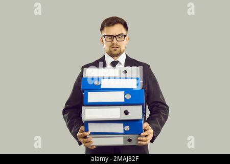 Angry office worker with pile of papers and documents is stressed by lot of work and deadlines. Stock Photo