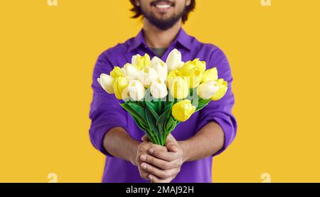 Hands man stretching forward bouquet of yellow tulip flowers for girlfriend during romantic date Stock Photo