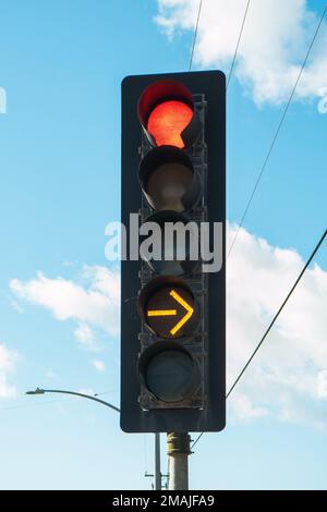 Red color and yellow arrow on the traffic light with cloudy sky on the background, vertical immage Stock Photo