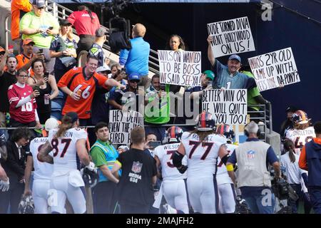 Seattle Seahawks fans hold signs mocking the Denver Broncos, including  quarterback Russell Wilson (3), a former Seahawk, as the Broncos leave the  field after warmups before an NFL football game, Monday, Sept.