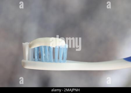 Toothbrush and toothpaste close up on gray blurred background. Stock Photo