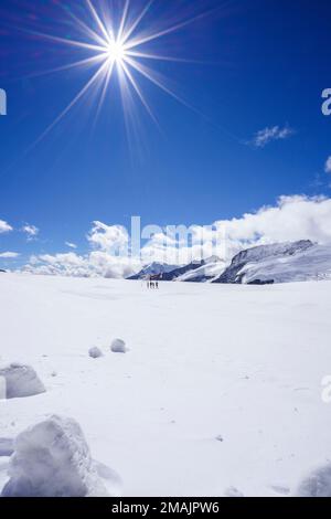 Swiss helicopter with red and white stars stands on Aletsch Glacier low angle view. Helikopter, blue sky with clouds. Grindelwald, Switzerland Stock Photo