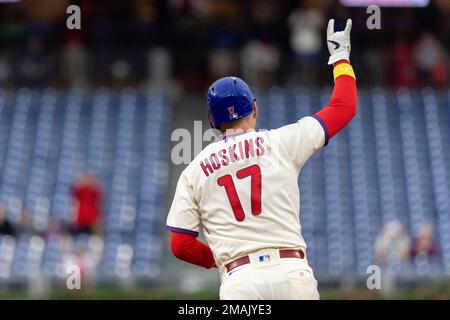 Philadelphia Phillies - Rhys Hoskins, wearing the cream Phillies uniform,  celebrating with the dugout after scoring a run.