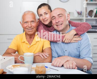 Happy family of three drinking tea in the kitchen Stock Photo