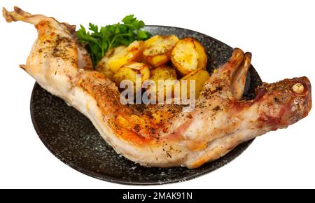 Whole baked young leveret with potatoes and greens Stock Photo