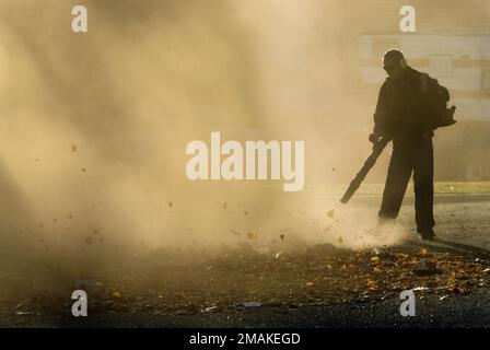 Man using backpack leaf blower in silhouette Stock Photo