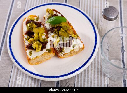 Sandwiches with cream cheese, sun-dried tomatoes, olives and pesto Stock Photo