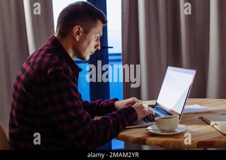 Man working at laptop at home. Freelance or distance job concept. Stock Photo