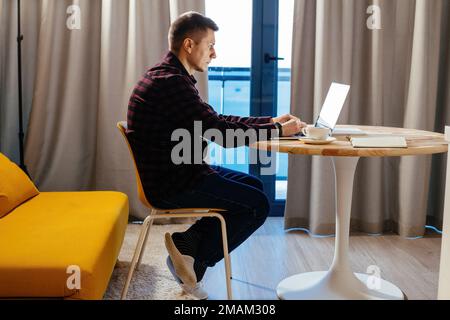 Man working at laptop at home. Freelance or distance job concept. Stock Photo