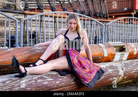 Hayleigh Young, a beautiful and fashionable woman poses for photograph beside the RRS Discovery ship on an icy cold winters day in Dundee, Scotland Stock Photo