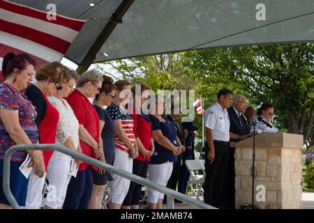 Attendees of the Memorial Day ceremony bow their heads as Joe Walts, right, delivers an invocation at the Fort Sam Houston Cemetery on Joint Base San Antonio - Fort Sam Houston, Texas, May 30, 2022. The Memorial Day ceremony was held to honor all fallen military members who died during their service in the U.S. Armed Forces. Stock Photo