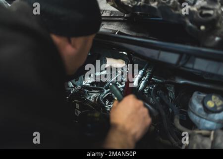 A skilled mechanic works diligently on a car with its hood raised to reveal the engine. High-quality photo Stock Photo