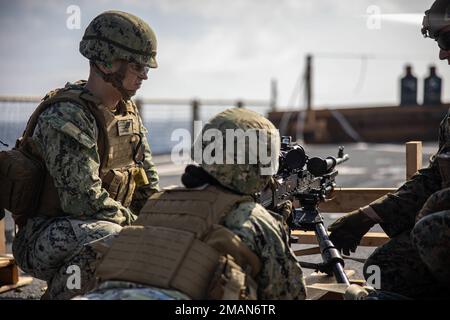 U.S. Navy equipment operator constructionman Ty Mathis and builder petty officer 3rd class Hannah Doge, with 31st Marine Expeditionary Unit, prepare to fire an M240B machine gun during a live fire deck shoot aboard the amphibious dock landing ship USS Rushmore (LSD 47) in the Philippine Sea, Aug. 28, 2022. Marines and Sailors conducted weapons training to further educate their Marines on different weapons platforms. The 31st MEU is operating aboard ships of the Tripoli Amphibious Ready Group in the 7th Fleet area of operations to enhance interoperability with allies and partners and serve as a Stock Photo