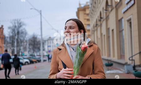 Happy brown-haired girl in a black jacket walks through the city in early spring. Stock Photo