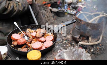 Homeless people fry food in the woods near the landfill. Stock Photo