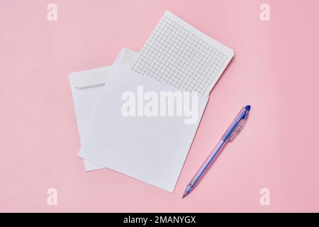 an open notebook, pen and paper on a pink background with copy - up sheets in the top right corner Stock Photo
