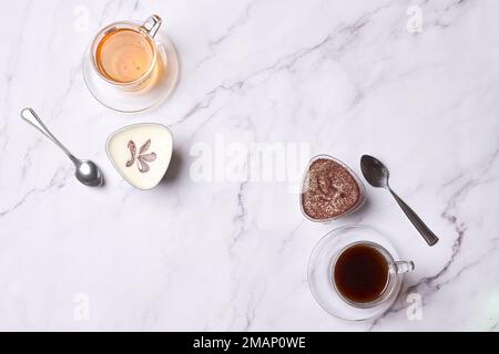 two cups of tea and spoons on a marble table with white marble countertops in the photo is taken from above Stock Photo