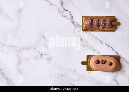 two pastries on a white marble counter top, one has chocolate and the other is covered with icing Stock Photo