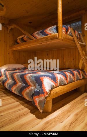 Rustic bunk beds made of logs in guest bedroom in basement  inside Scandinavian style log home. Stock Photo