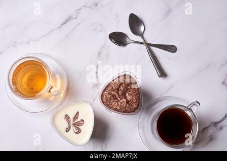 some teas and spoons on a white marble countertop with two cups filled with different types of tea Stock Photo