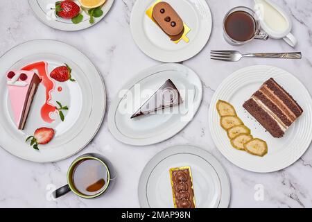 various desserts on white plates with forks and spoons next to each other plated items in the table Stock Photo