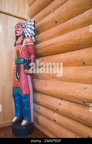 Wooden Indian Chief sculpture in living room inside Scandinavian style log home. Stock Photo