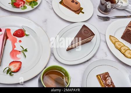 some desserts on plates with cups and spoons next to each other plated up in the same place Stock Photo