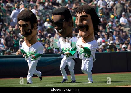 Mascots representing former Oakland Athletics Rollie Fingers, from left,  Rickey Henderson and Dennis Eckersley wait before racing during a baseball  game between the Athletics and the New York Yankees in Oakland, Calif.,  Sunday, Aug. 28, 2022. (AP