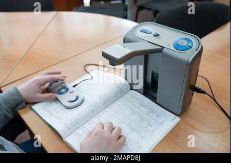 A visually impaired man uses a scanning and reading machine. Stock Photo