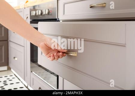 Woman opening drawer in modern kitchen, closeup Stock Photo
