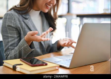 Confident millennial Asian businesswoman or female marketing manager having an online meeting with her team, pitching new project through online video Stock Photo