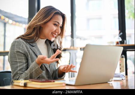 Professional and confident millennial Asian businesswoman or female marketing manager having an online meeting with her team, pitching new project thr Stock Photo