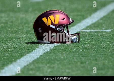 FILE - Washington Commanders helmets with Guardian Caps sit on the field  during practice at the team's NFL football training facility, Saturday,  July 30, 2022 in Ashburn, Va. The mushroom-like contraptions NFL