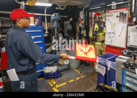 PHILIPPINE SEA (June 6, 2022) Damage Controlman Fireman Ethan Heffner (right), from New Orleans, checks for heat signatures while Boatswain’s Mate 2nd Class Shontez Grays (left), from Cleveland, simulates a class-A fire in the general workshop aboard Arleigh Burke-class guided-missile destroyer USS Benfold (DDG 65) during a firefighting drill. Benfold is assigned to Commander, Task Force (CTF) 71/Destroyer Squadron (DESRON) 15, the Navy’s largest forward-deployed DESRON and the U.S. 7th Fleet’s principal surface force. Stock Photo