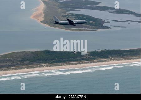 A KC-46A Pegasus assigned to the 916th Air Refueling Wing at Seymour Johnson Air Force Base, North Carolina, flies over a lighthouse off the coast of North Carolina, June 6, 2022. The KC-46 is a multicapable aircraft that can perform aerial refueling, cargo and aeromedical evacuation capabilities. Stock Photo