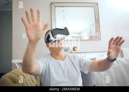 Technology truly is amazing. a mature man using a VR headset at home. Stock Photo