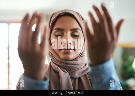 Pray as though everything depended on God. a young muslim woman praying in the lounge at home. Stock Photo