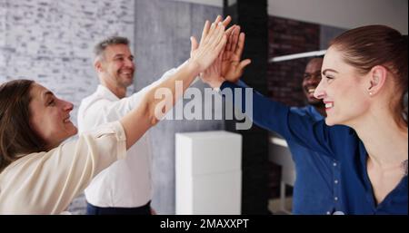 Happy Businesspeople Giving High Five Over Desk At Workplace Stock Photo