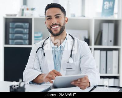 Your friendly neighbourhood general practitioner. a young doctor using a digital tablet in an office. Stock Photo