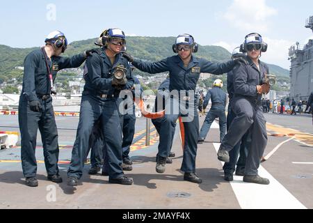 220609-N-IL330-1130 SASEBO, Japan (June 9, 2022) – Sailors fight a simulated fire during a flight deck firefighting drill aboard amphibious assault carrier USS Tripoli (LHA 7), June 9, 2022. Tripoli is operating in the U.S. 7th Fleet area of operations to enhance interoperability with allies and partners and serve as a ready response force to defend peace and maintain stability in the Indo-Pacific region. Stock Photo