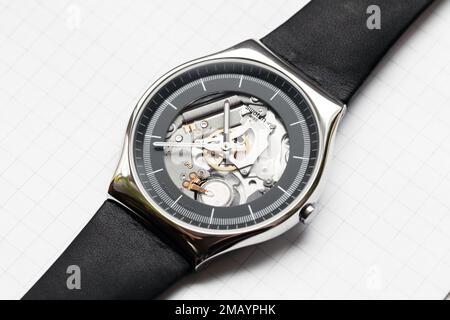 Biel, Switzerland - October 28, 2021: Swiss made quartz Black Skeleton wrist watch by Swatch lays on a white table, close-up studio photo Stock Photo