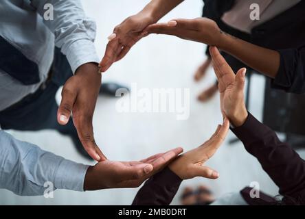 We are part of the circle of life. High angle shot of a group of unidentifiable businesspeople forming a circle with their hands. Stock Photo