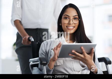Im on top things. Cropped portrait of an attractive young businesswoman in a wheelchair using her tablet in the office. Stock Photo